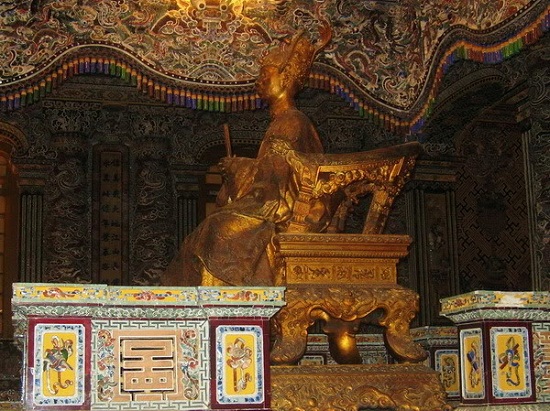 Tượng Vua đồng ngồi trên ngai, phía dưới là thi hài của Vua