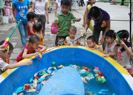 ​Hàng chục trẻ nhỏ háo hức quây quanh chiếc bể nhỏ để câu cá giả.